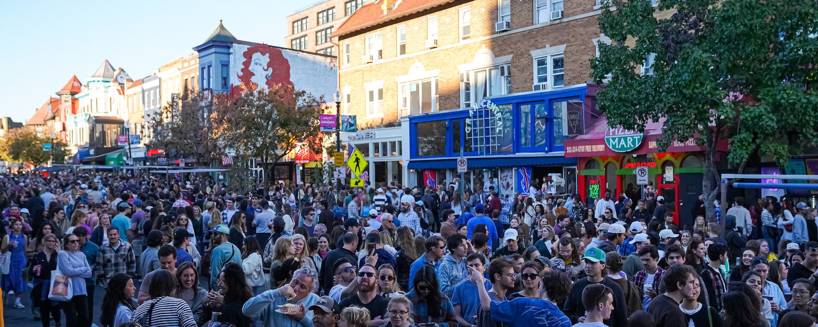 A bustling crowd fills the streets of Adams Morgan in Washington, DC, during a lively festival.
