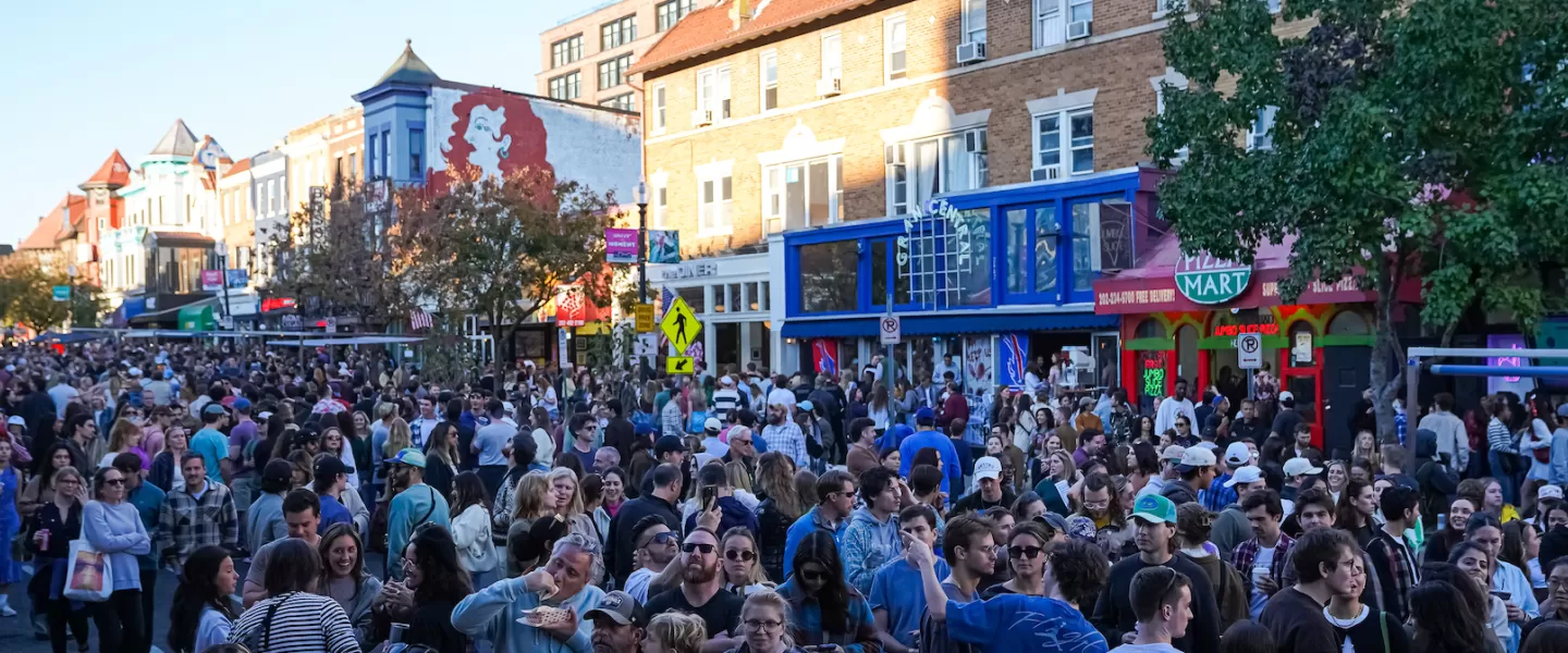 A bustling crowd fills the streets of Adams Morgan in Washington, DC, during a lively festival.